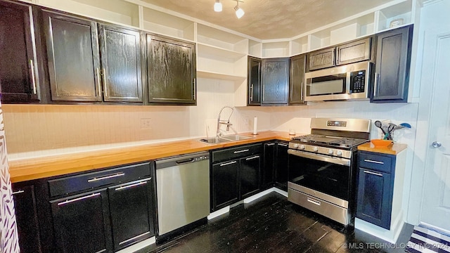 kitchen with stainless steel appliances, dark brown cabinets, sink, and wooden counters