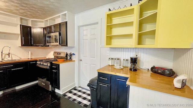 kitchen with appliances with stainless steel finishes, a textured ceiling, wooden counters, and sink