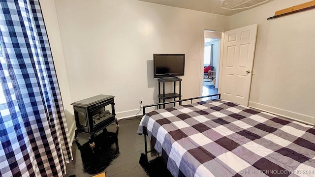 unfurnished bedroom with dark wood-type flooring and a wood stove