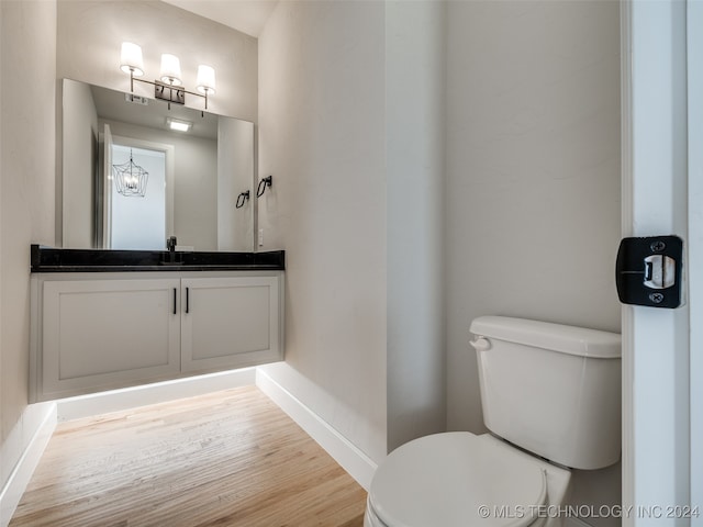 bathroom featuring vanity, toilet, wood-type flooring, and a chandelier