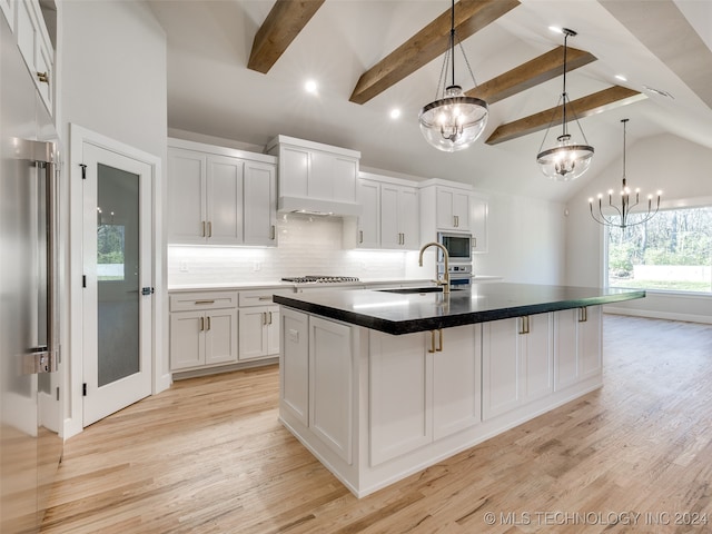 kitchen with an inviting chandelier, white cabinets, a spacious island, light wood-type flooring, and appliances with stainless steel finishes