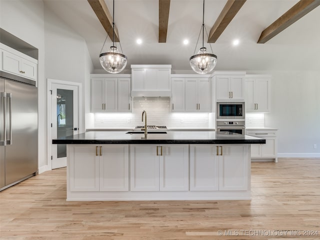 kitchen with built in appliances, white cabinetry, a center island with sink, and beamed ceiling