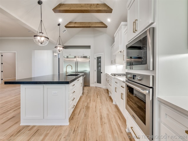 kitchen with lofted ceiling with beams, white cabinetry, an island with sink, and stainless steel appliances