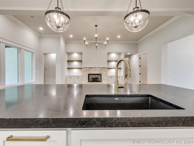 kitchen featuring a chandelier, pendant lighting, a stone fireplace, and sink