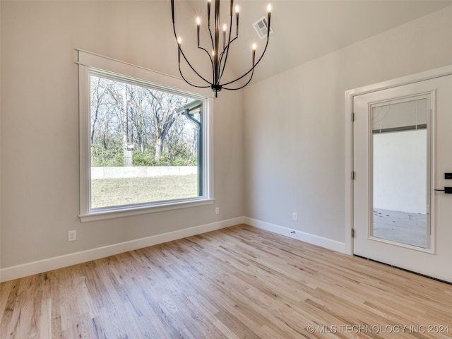 unfurnished dining area with a chandelier and light hardwood / wood-style floors