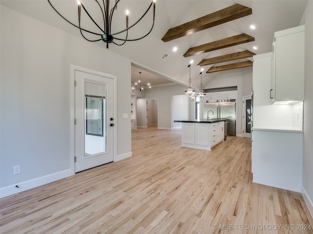 kitchen with white cabinetry, hanging light fixtures, light hardwood / wood-style flooring, lofted ceiling with beams, and an island with sink