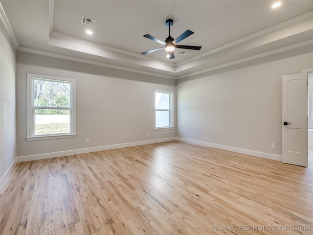 unfurnished room featuring light hardwood / wood-style floors, crown molding, plenty of natural light, and a tray ceiling