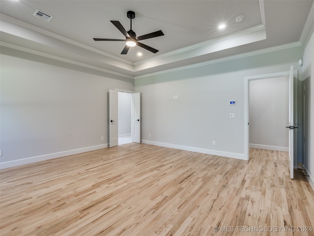 empty room featuring a tray ceiling, crown molding, ceiling fan, and light hardwood / wood-style floors