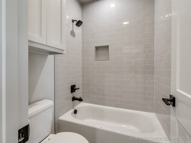 bathroom featuring tiled shower / bath combo and toilet