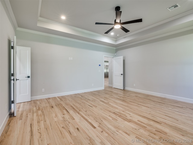 unfurnished room with ceiling fan, light hardwood / wood-style floors, ornamental molding, and a tray ceiling