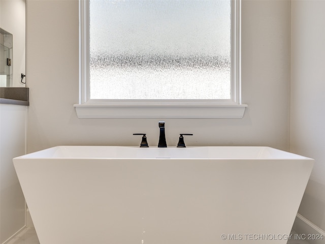 bathroom featuring a healthy amount of sunlight and a tub to relax in