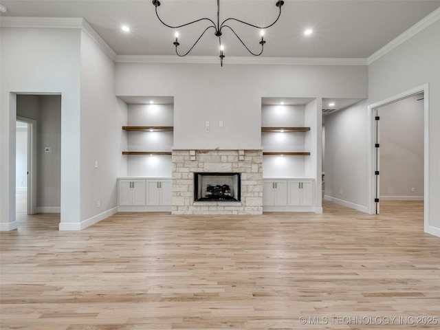 unfurnished living room featuring crown molding, a stone fireplace, a notable chandelier, and light hardwood / wood-style floors