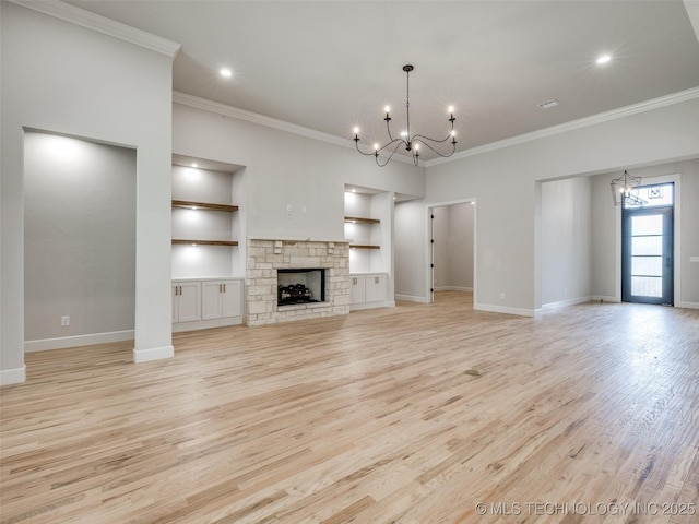 unfurnished living room with an inviting chandelier, a fireplace, light hardwood / wood-style floors, and crown molding