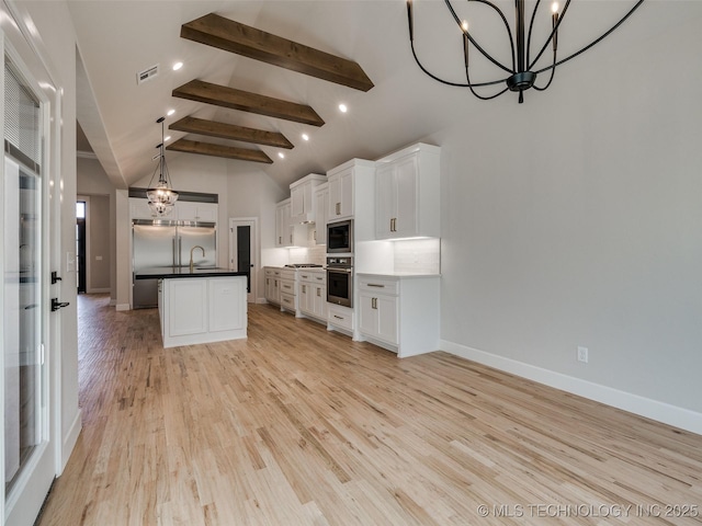 kitchen with a kitchen island, white cabinets, a chandelier, hanging light fixtures, and built in appliances