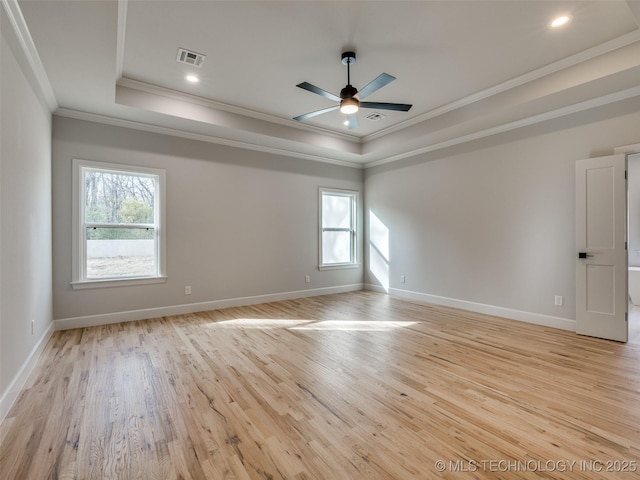 unfurnished room featuring ceiling fan, plenty of natural light, a tray ceiling, and light wood-type flooring