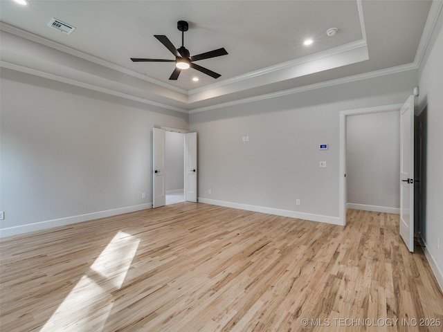 empty room featuring crown molding, light hardwood / wood-style flooring, a raised ceiling, and ceiling fan