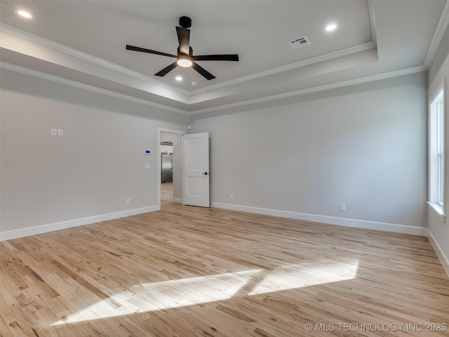 spare room with crown molding, light hardwood / wood-style flooring, ceiling fan, and a tray ceiling