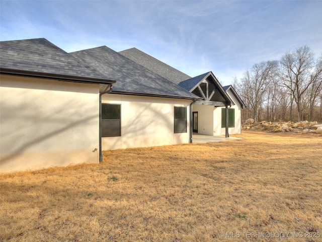 view of side of home featuring a patio and a lawn