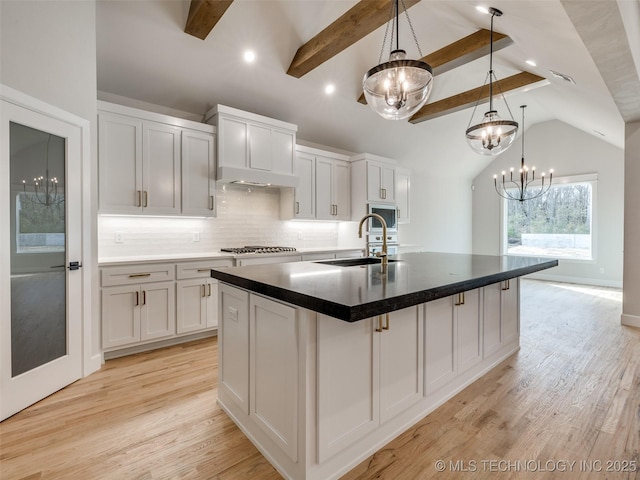 kitchen with white cabinetry, sink, pendant lighting, and a kitchen island with sink