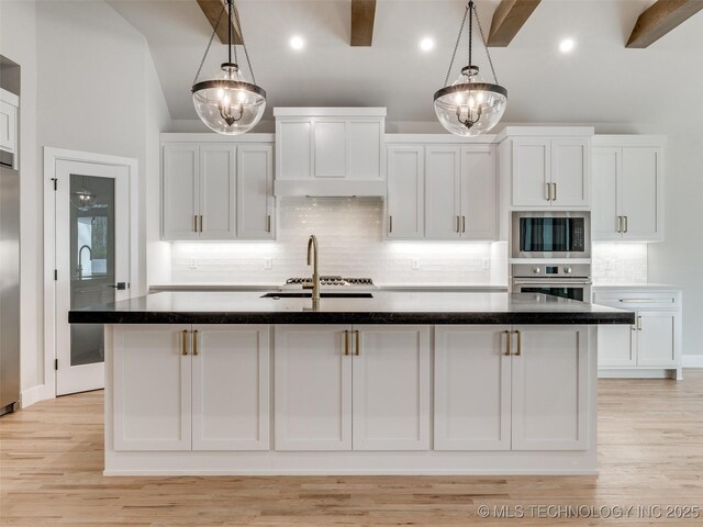 kitchen featuring white cabinetry, appliances with stainless steel finishes, pendant lighting, and a center island with sink