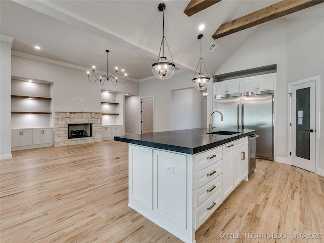 kitchen with sink, hanging light fixtures, a center island with sink, light hardwood / wood-style floors, and white cabinets