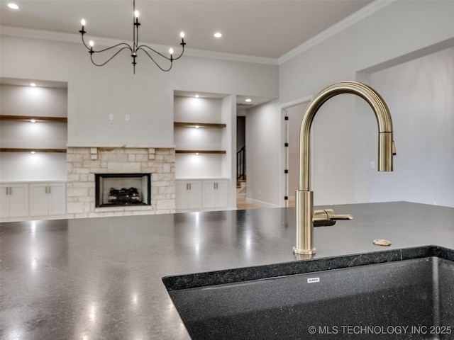 kitchen featuring sink, a stone fireplace, and ornamental molding