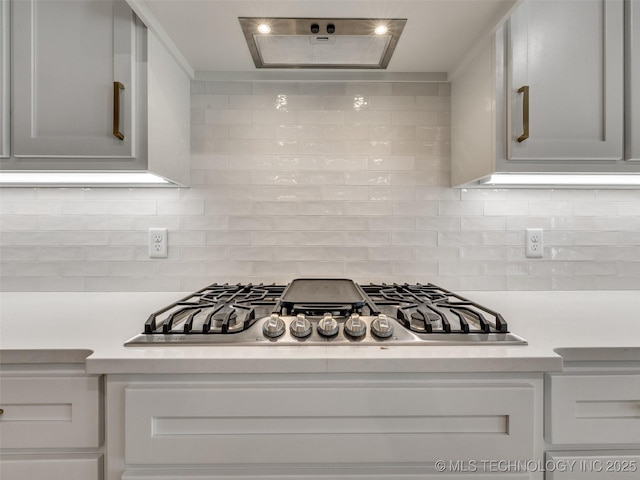 kitchen with white cabinets, backsplash, and stainless steel gas stovetop