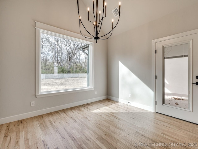 unfurnished dining area with an inviting chandelier and light hardwood / wood-style flooring