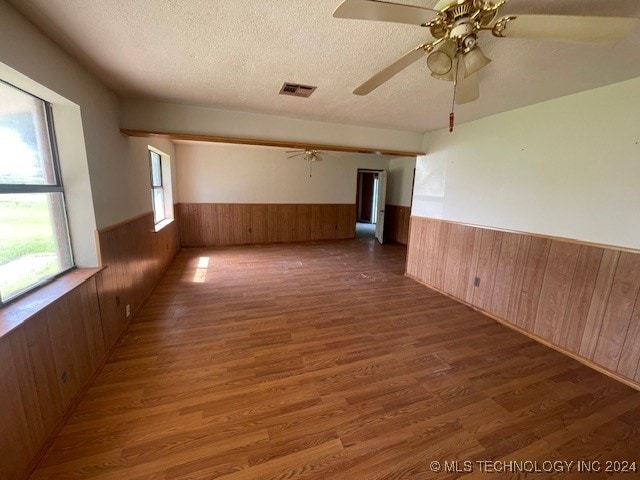 empty room featuring dark wood-type flooring, a healthy amount of sunlight, ceiling fan, and a textured ceiling