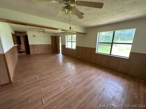 spare room featuring ceiling fan, a textured ceiling, and a healthy amount of sunlight