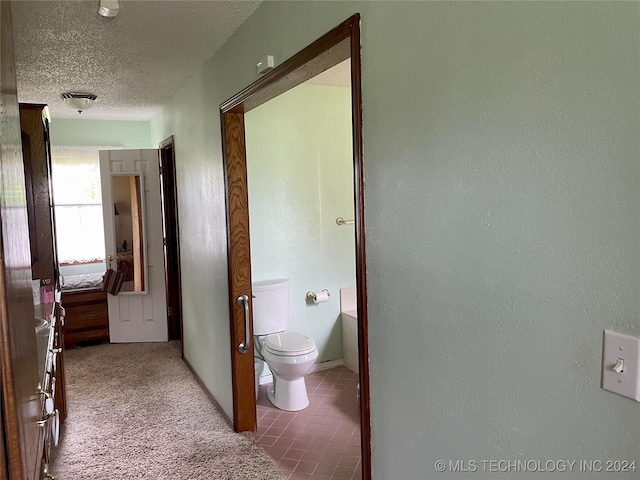 bathroom with toilet, tile patterned floors, and a textured ceiling