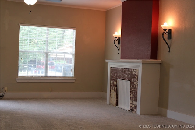 unfurnished living room featuring a healthy amount of sunlight, carpet, a fireplace, and crown molding