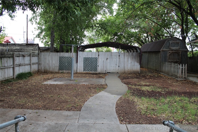 view of yard featuring an outbuilding, a carport, a storage unit, and fence