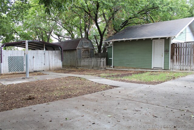 view of yard with a storage unit, an outdoor structure, fence, and a detached carport