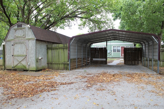 view of outdoor structure with fence and a carport