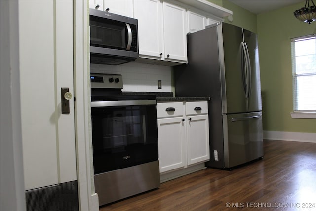 kitchen with dark wood-style flooring, dark countertops, backsplash, appliances with stainless steel finishes, and white cabinetry