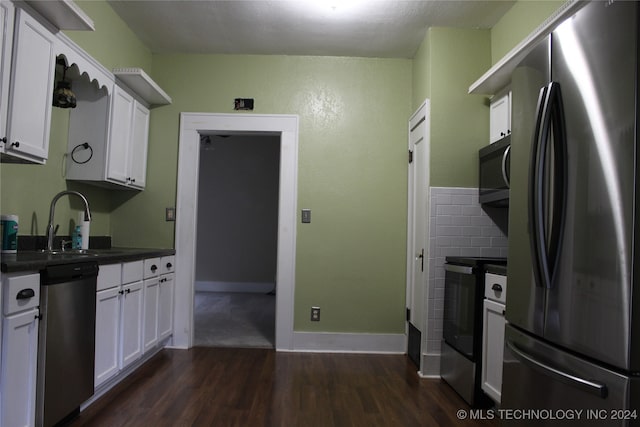 kitchen featuring dark wood-style flooring, a sink, white cabinets, appliances with stainless steel finishes, and dark countertops