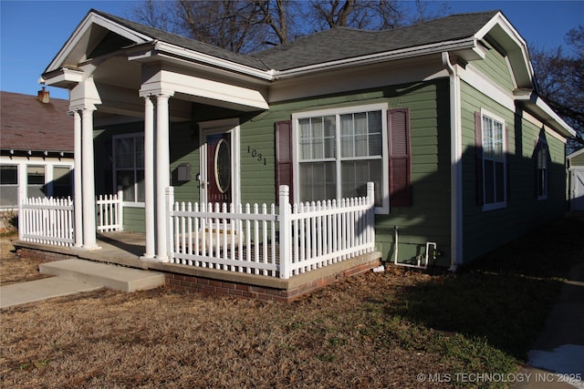 view of side of property with a porch, a shingled roof, and fence