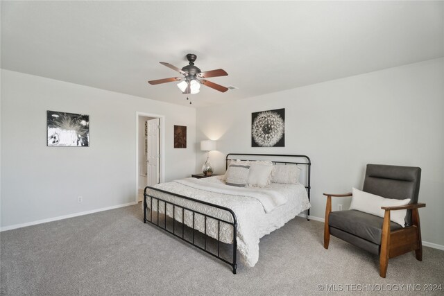 carpeted bedroom with ensuite bathroom and ceiling fan