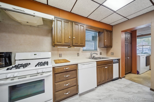 kitchen featuring washer / dryer, ventilation hood, sink, a drop ceiling, and white appliances