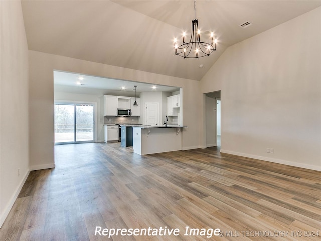 unfurnished living room featuring vaulted ceiling, a notable chandelier, sink, and light wood-type flooring