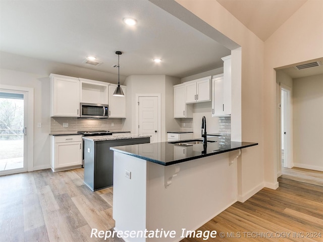 kitchen with pendant lighting, white cabinetry, kitchen peninsula, sink, and light hardwood / wood-style floors