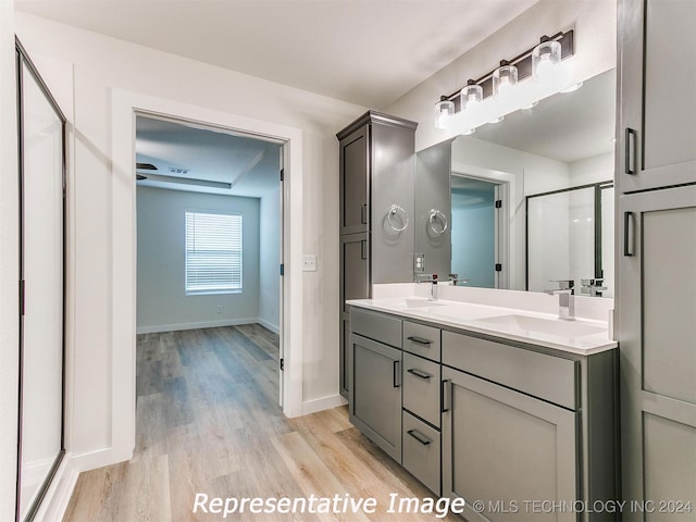 bathroom with hardwood / wood-style floors, a shower with door, and vanity