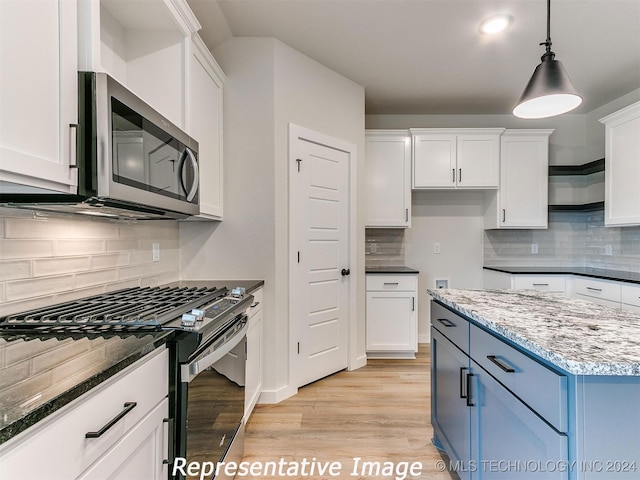 kitchen featuring light wood-type flooring, pendant lighting, stainless steel appliances, decorative backsplash, and white cabinets