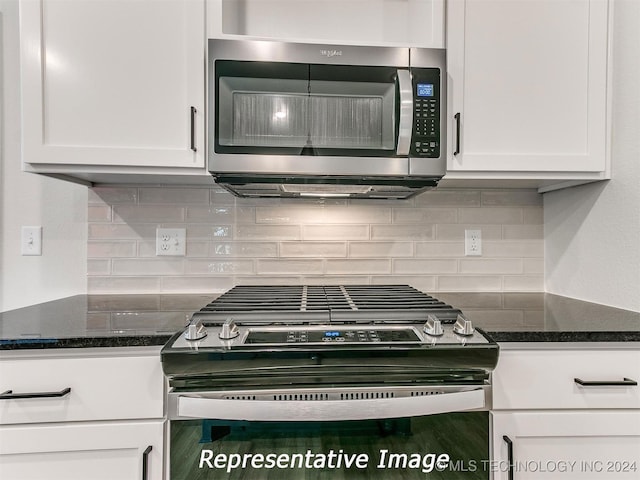 kitchen with dark stone countertops, stainless steel appliances, and white cabinetry