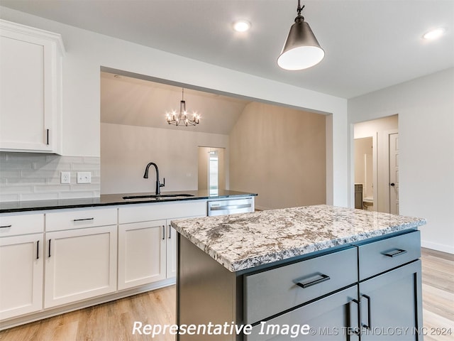 kitchen with light hardwood / wood-style floors, a center island, sink, dark stone countertops, and white cabinets