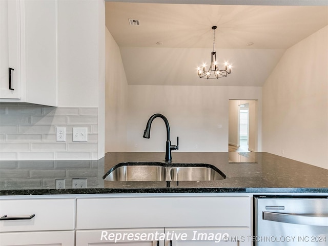 kitchen featuring dark stone countertops, dishwasher, white cabinetry, sink, and lofted ceiling