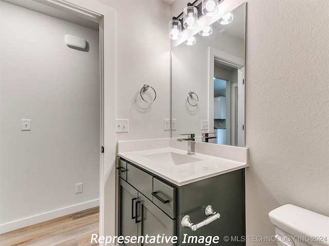 bathroom with wood-type flooring, toilet, and vanity