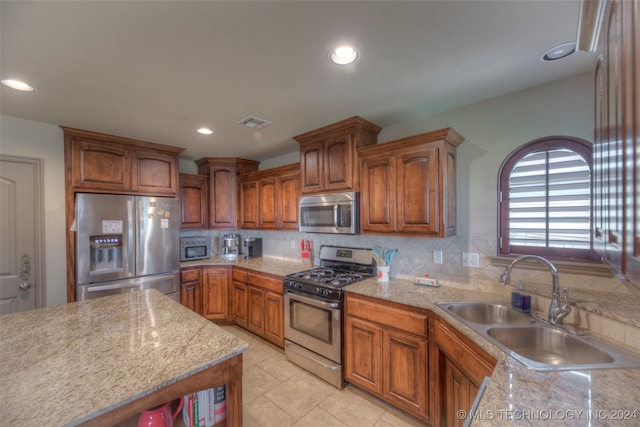 kitchen with backsplash, stainless steel appliances, light stone counters, sink, and light tile patterned flooring