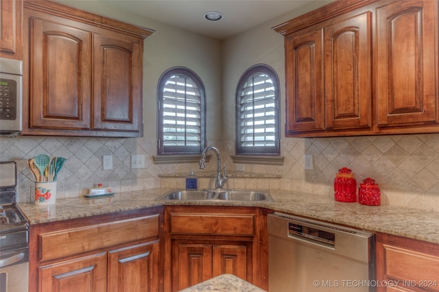 kitchen with tasteful backsplash, light stone countertops, stainless steel appliances, and sink